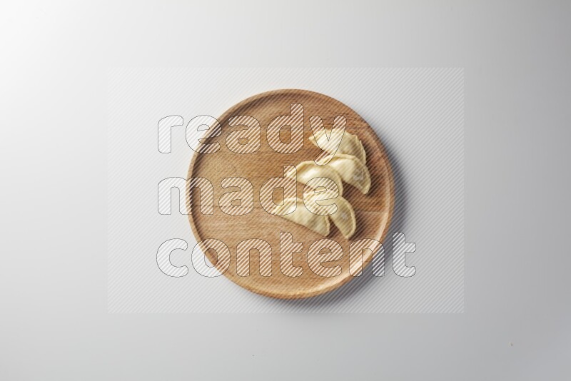 Five Sambosas on a wooden round plate on a white background