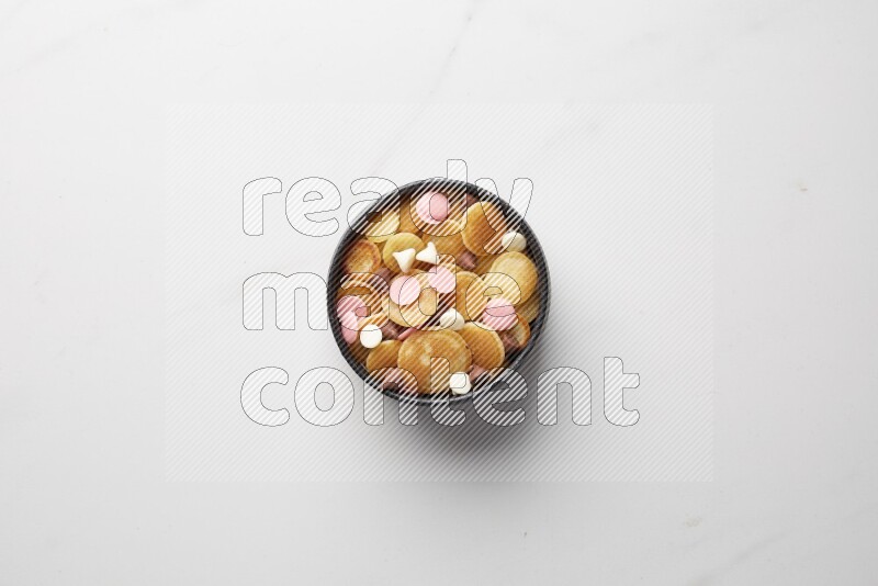 Top-view shot of mixed chocolate chips cereal pancakes in a round bowl on white background