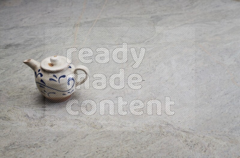 A pottery teapot on grey marble background