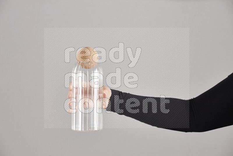 A woman in black abaya holding different glassware in different positions