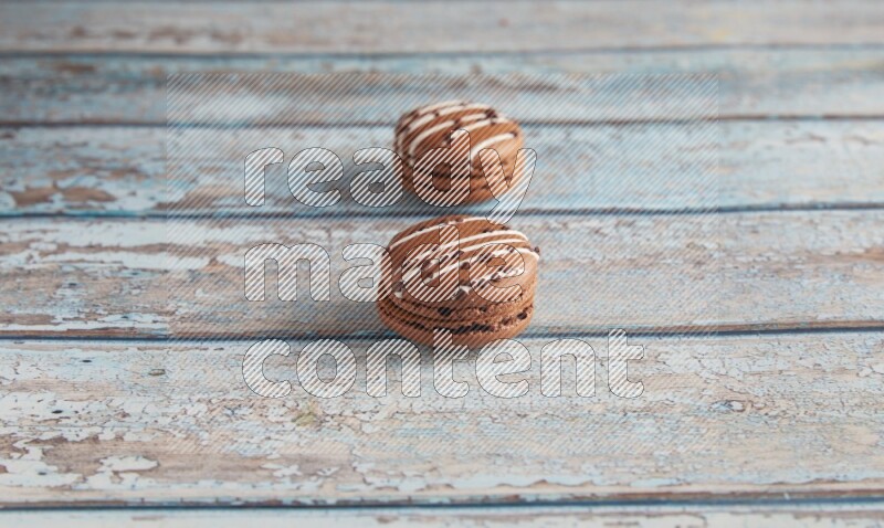 45º Shot of two Brown white  Chocolate Caramel macarons on light blue wooden background