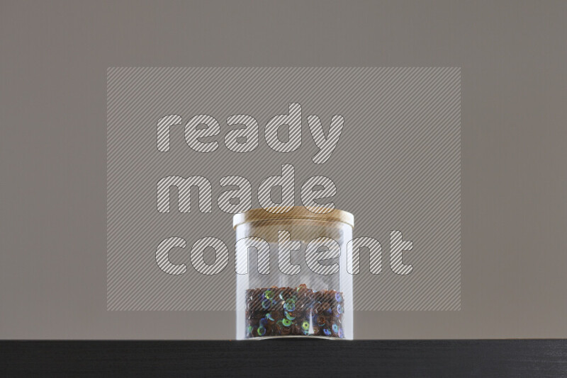 Sequins in a glass jar on black background