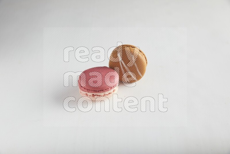 45º Shot of of two assorted Brown Irish Cream, and Pink Litchi Raspberry macarons on white background