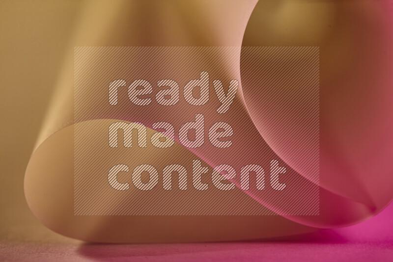 An abstract art piece displaying smooth curves in gold and pink gradients created by colored light