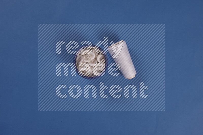 A white collection of sewing and tailoring tools arranged on a blue background