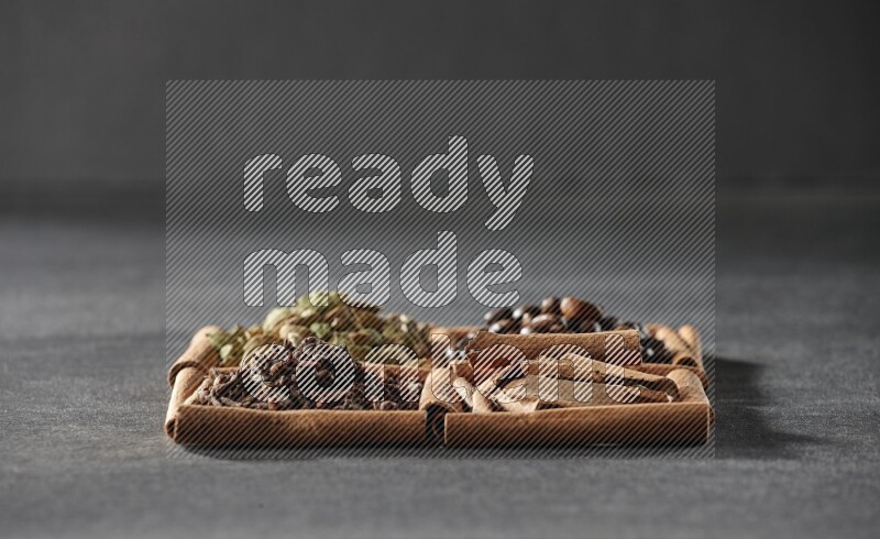 4 squares of cinnamon sticks full of coffee beans, cinnamon, cloves and cardamom on black flooring