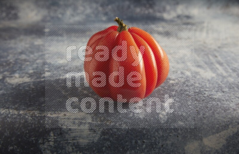 45 degree single heirloom tomato on a textured rustic blue background