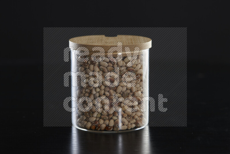 Black-eyed peas in a glass jar on black background
