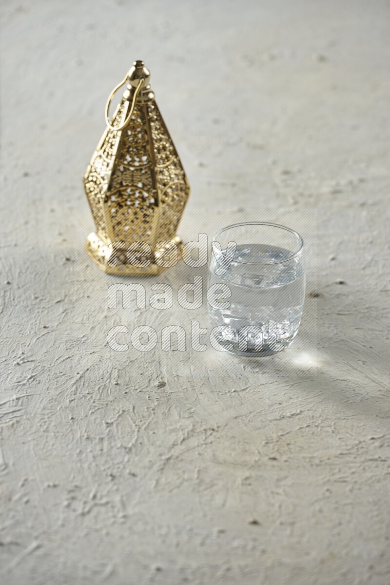 A golden lantern with different drinks, dates, nuts, prayer beads and quran on textured white background