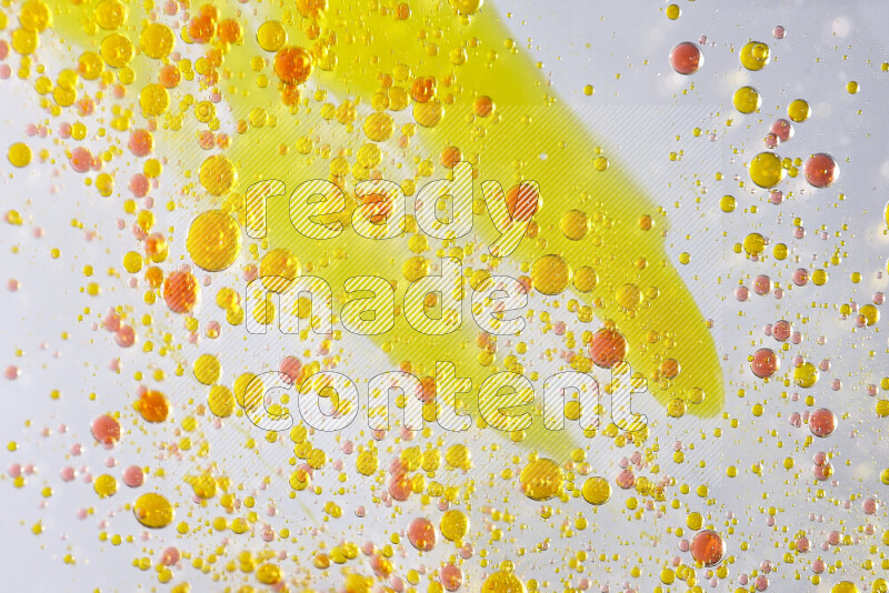 Close-ups of abstract yellow and red watercolor drops on oil Surface on white background