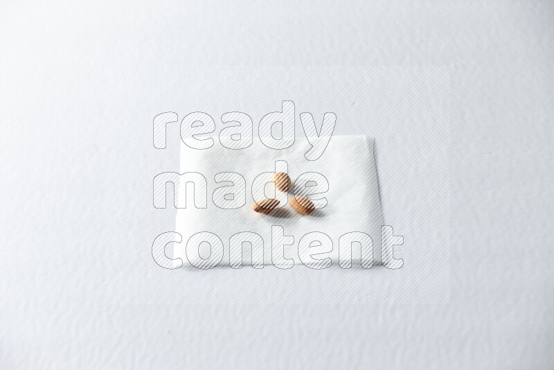 3 peeled almonds on a piece of paper on a white background in different angles