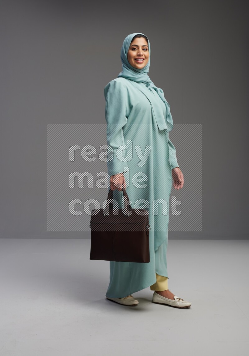 Saudi Woman wearing Abaya standing holding bag on Gray background