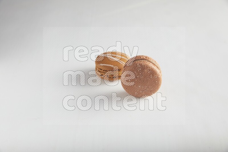 45º Shot of of two assorted Brown Irish Cream, and Brown Hazelnuts macarons on white background