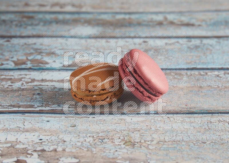 45º Shot of of two assorted Brown Irish Cream, and Pink Raspberry macarons on light blue background