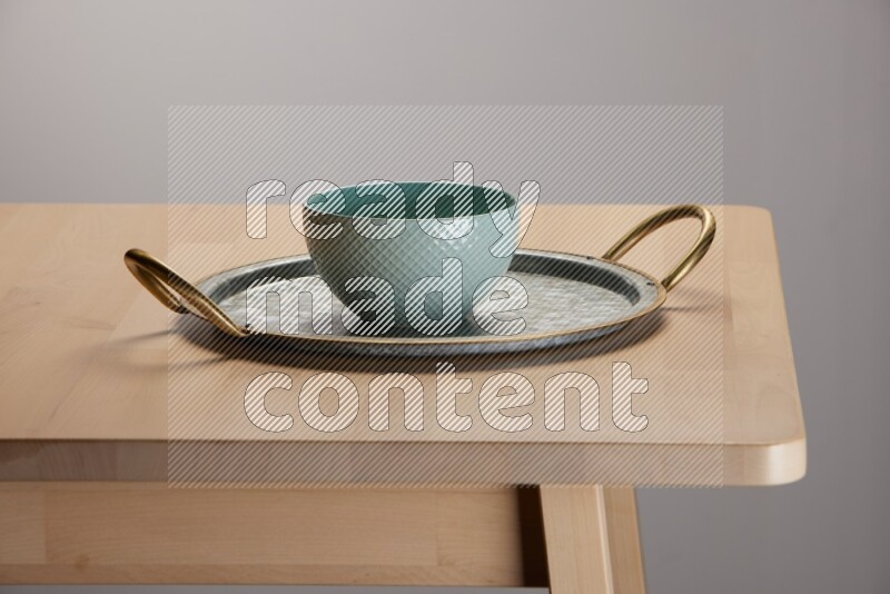 blue bowl placed on a rounded stainless steel metal tray with golden handels on the edge of wooden table