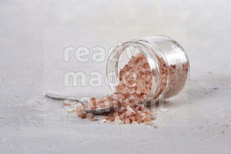A glass jar full of coarse himalayan salt crystals on white background