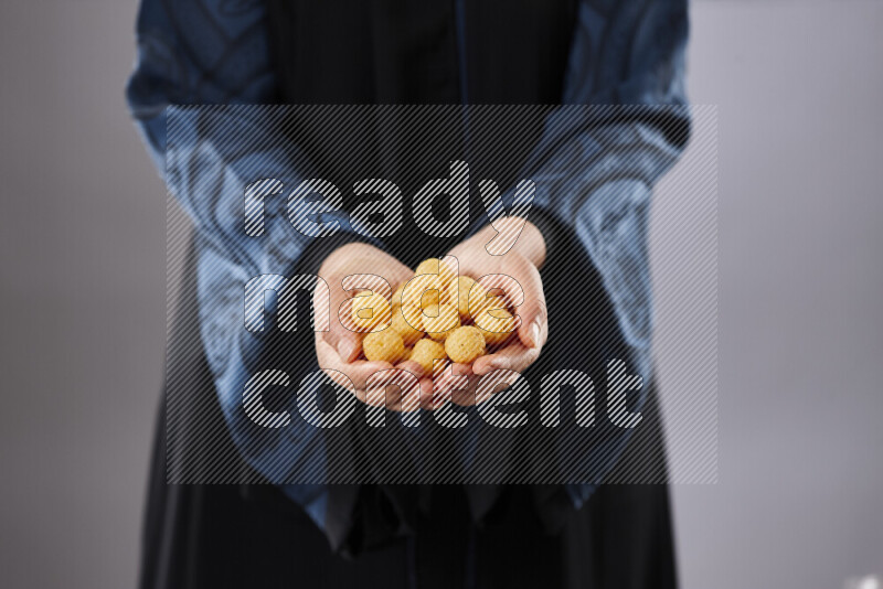 Woman in abaya holding different kinds of snacks in different positions