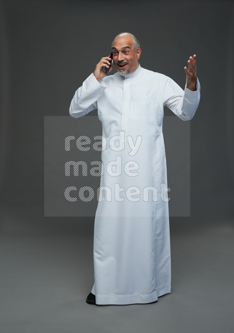 Saudi man without shomag Standing talking on phone on gray background
