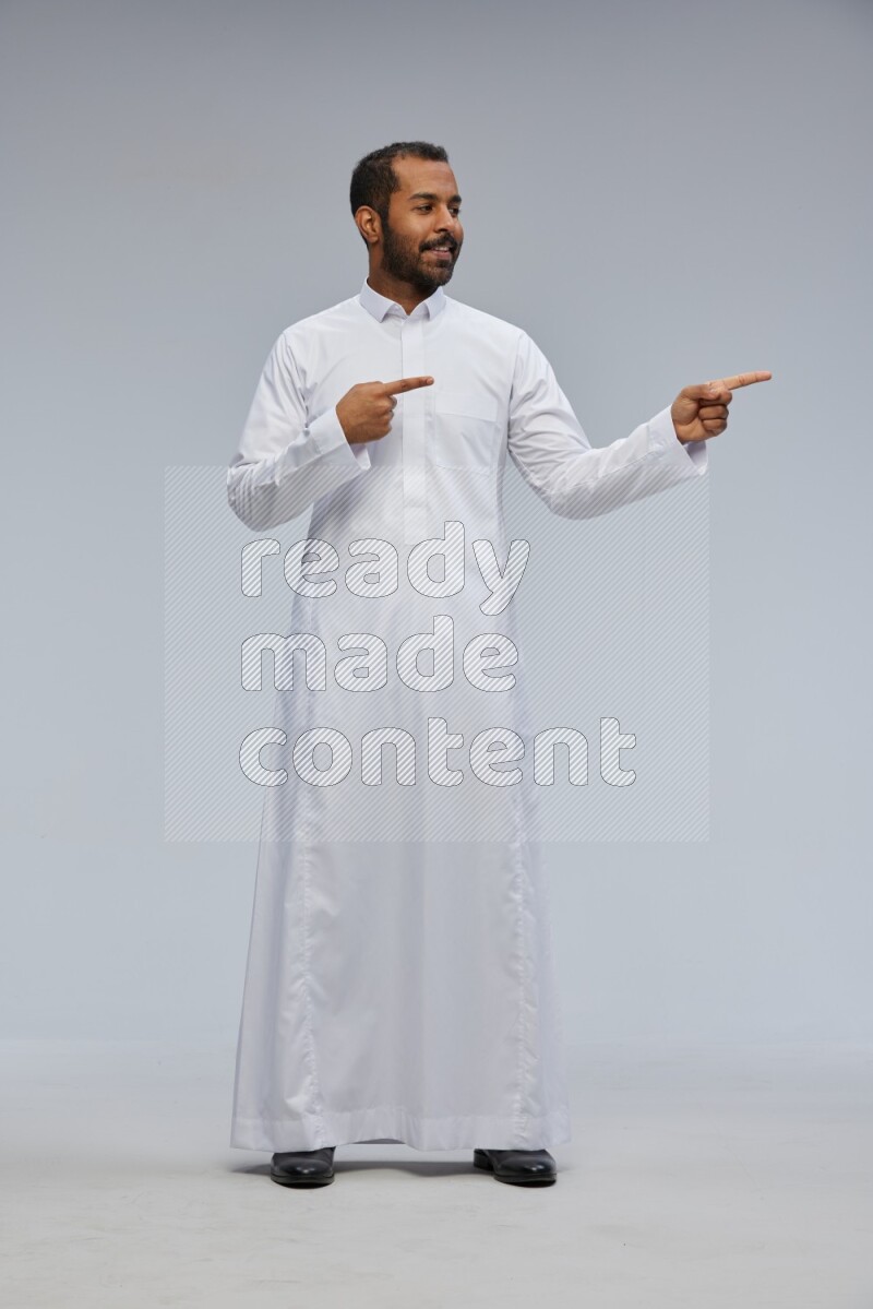 Saudi man Wearing Thob standing interacting with the camera on Gray background