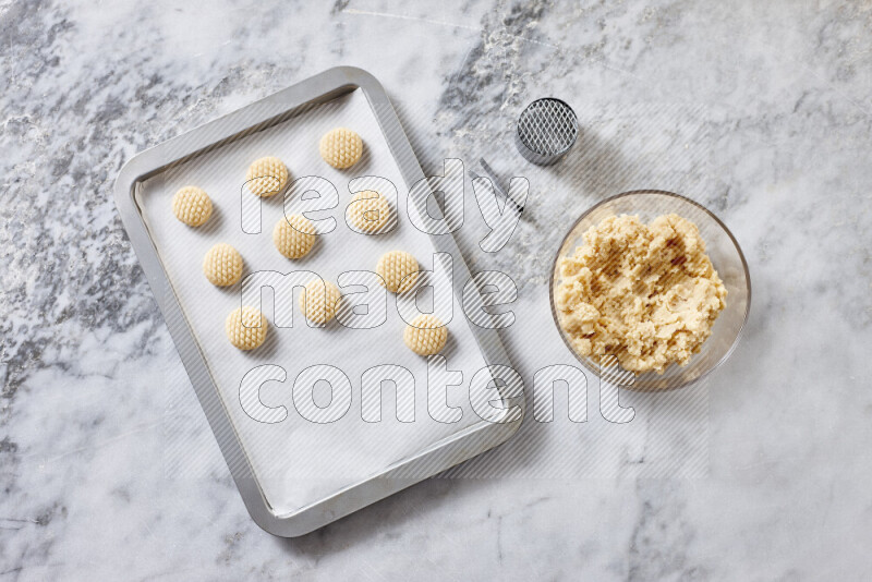 كحك خطوة بخطوة بمكوناته سمن، سكر، دقيق، سمسم، خميرة، ماء ونكهة الكحك على خلفية رخام رمادي