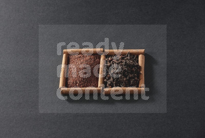 مربعان من أعواد القرفة ممتلئان بحب الرشاد والقرنفل علي خلفية سوداء