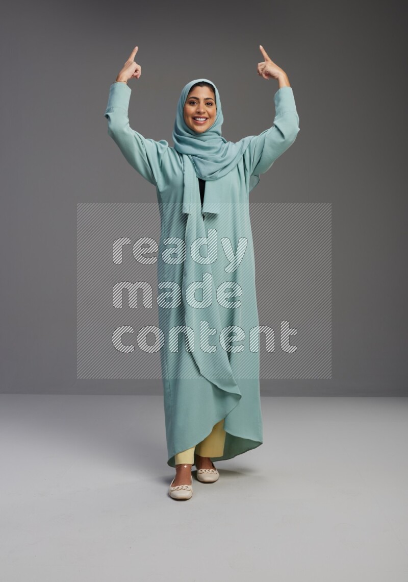 Saudi Woman wearing Abaya standing interacting with the camera on Gray background