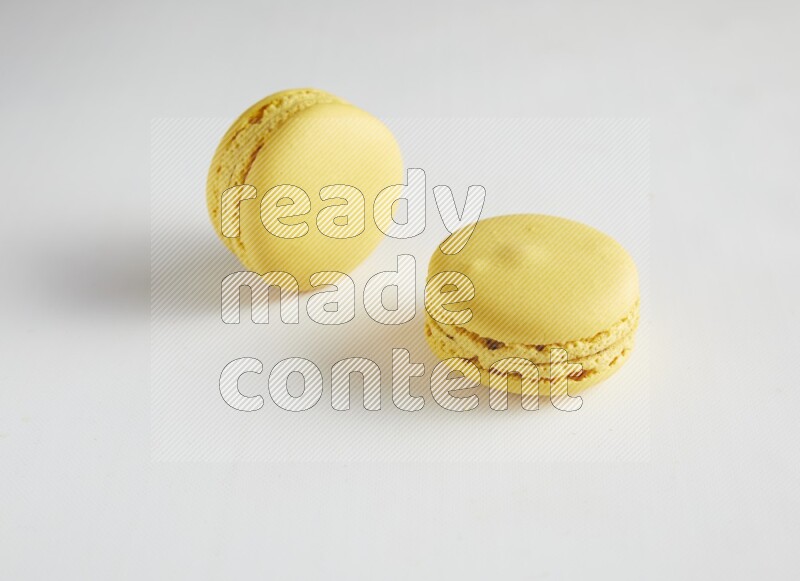 45º Shot of two Yellow Lemon macarons on white background