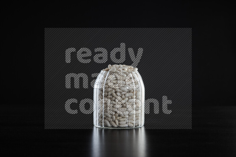 White beans in a glass jar on black background