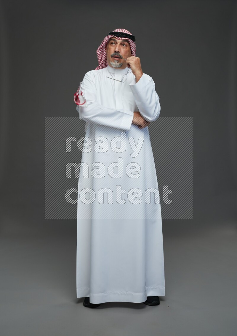 Saudi man with shomag Standing Interacting with the camera on gray background