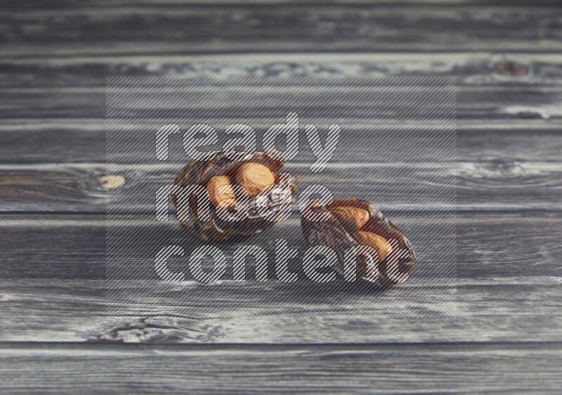 two almond stuffed madjoul dates on a wooden grey background