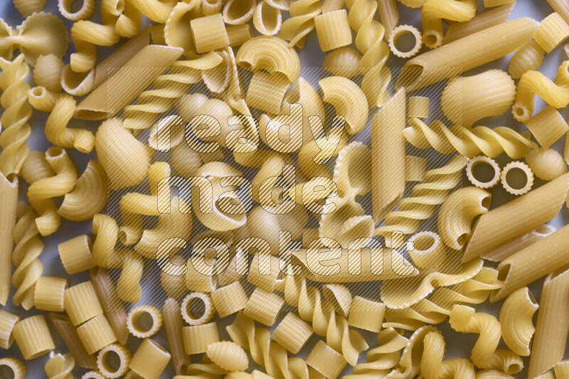 Different pasta types on light blue background