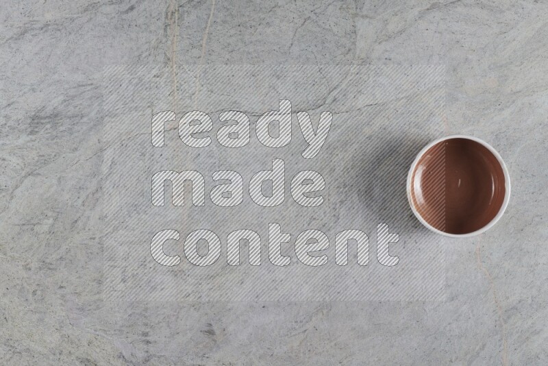 A brown pottery bowl on grey marble background