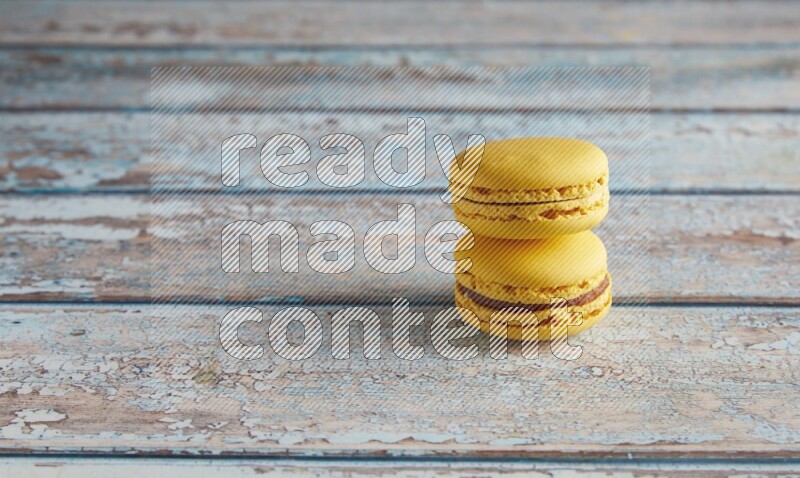 45º Shot of two Yellow Lemon macarons on light blue wooden background