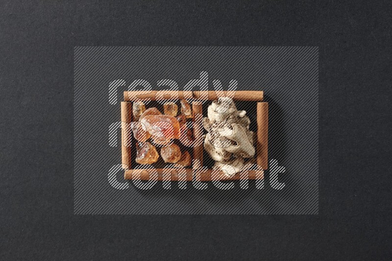2 squares of cinnamon sticks full of dried ginger and gum arabic on black flooring