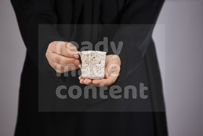 A woman in black abaya holding different pottery essentials in different positions