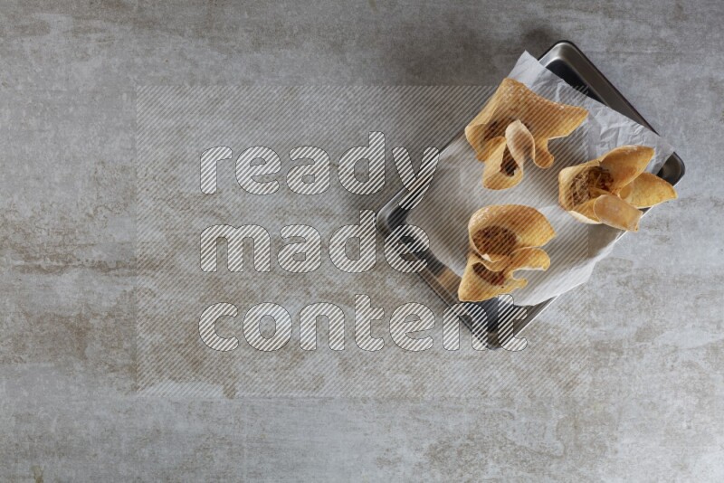 wonton cups on parchment paper in stainless tray on grey textured counter top