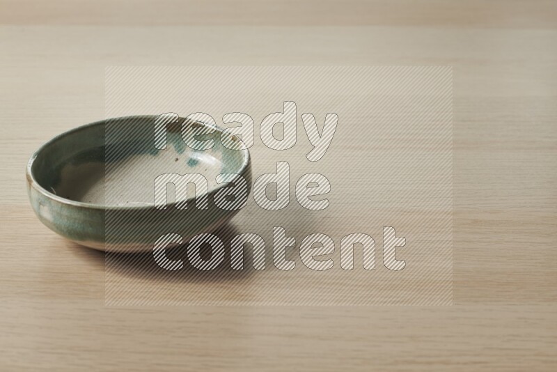 وعاء فخاري متعدد الألوان على خلفية خشبية فاتحة