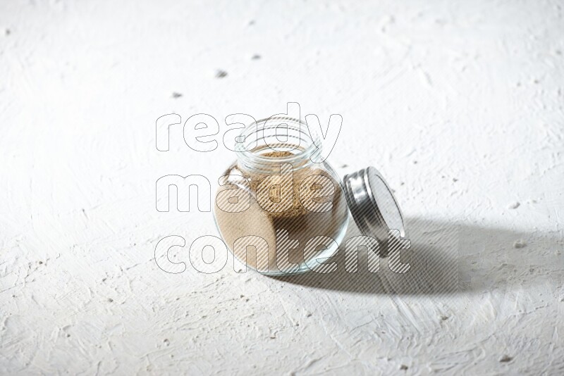 وعاء زجاجي ممتلئ ببودرة الكمون على خلفية بيضاء