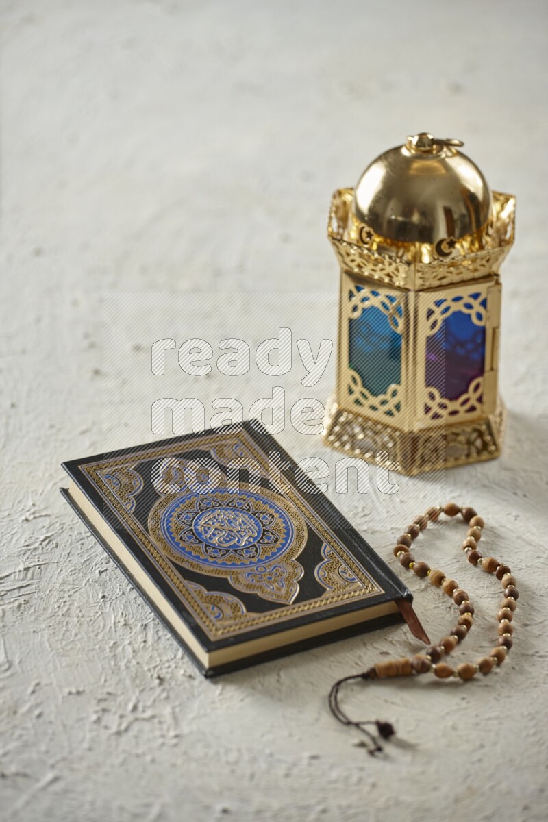 A golden lantern with different drinks, dates, nuts, prayer beads and quran on textured white background