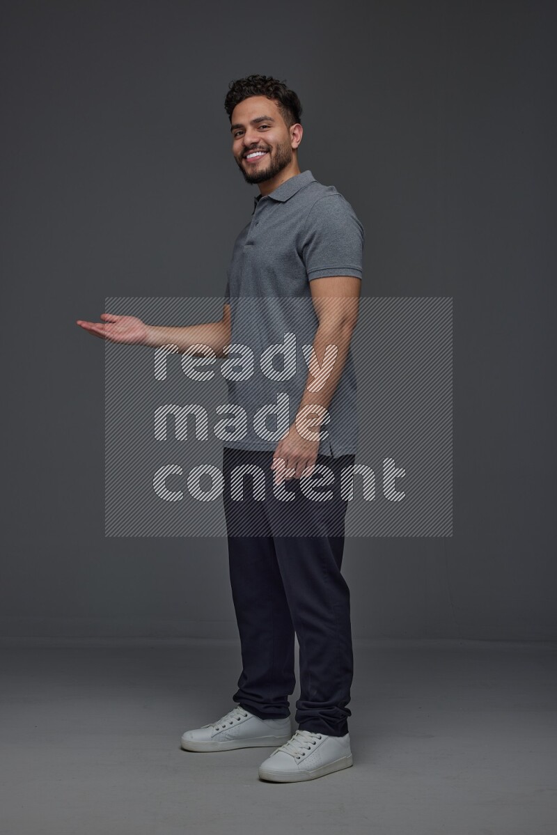 A man wearing casual standing and making multi hand gestures eye level on a gray background