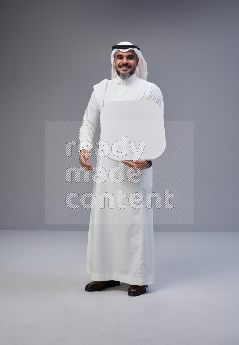 Saudi man Wearing Thob and white Shomag standing holding social media sign on Gray background