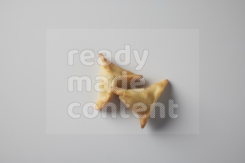 Two fried sambosa from a top angle on a white background