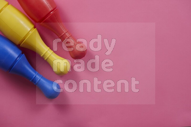 أوتاد البولينج البلاستيكية الملونة علي خلفيات ملونة مختلفة (ألعاب أطفال)