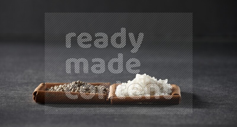 2 squares of cinnamon sticks full of white pepper and salt on black flooring