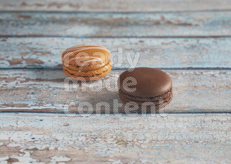 45º Shot of of two assorted Brown Irish Cream, and Brown Dark Chocolate macarons on light blue background