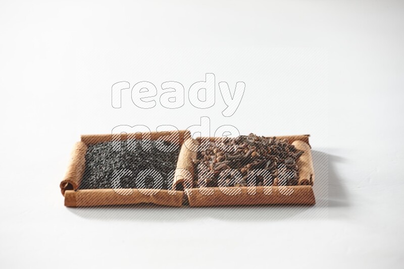 2 squares of cinnamon sticks full of cloves and black seeds on white flooring