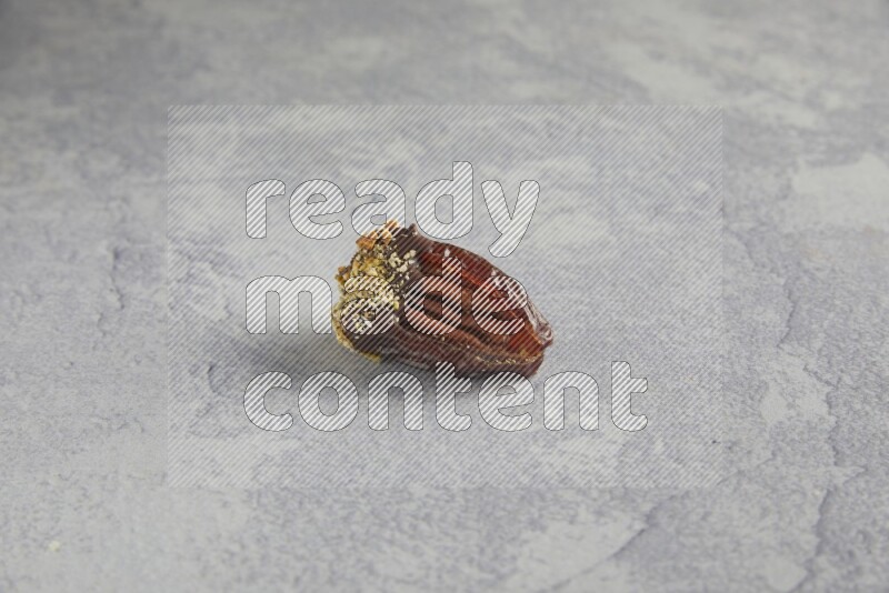 pecan stuffed date covered with Dark chocolate and chopped pistachios on alight grey background