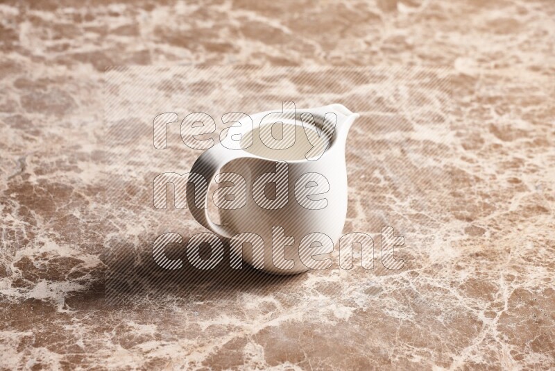 A ceramic milk jug on beige marble background