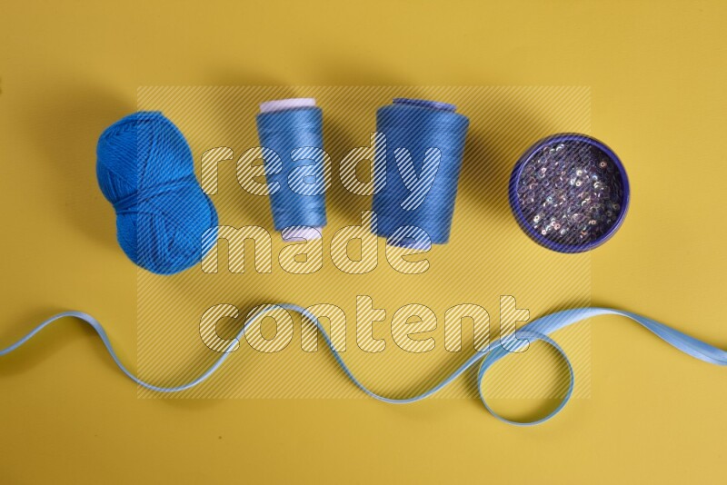 A blue collection of sewing and tailoring tools arranged on a yellow background