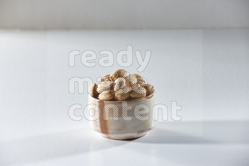 A beige ceramic bowl full of almonds on a white background in different angles